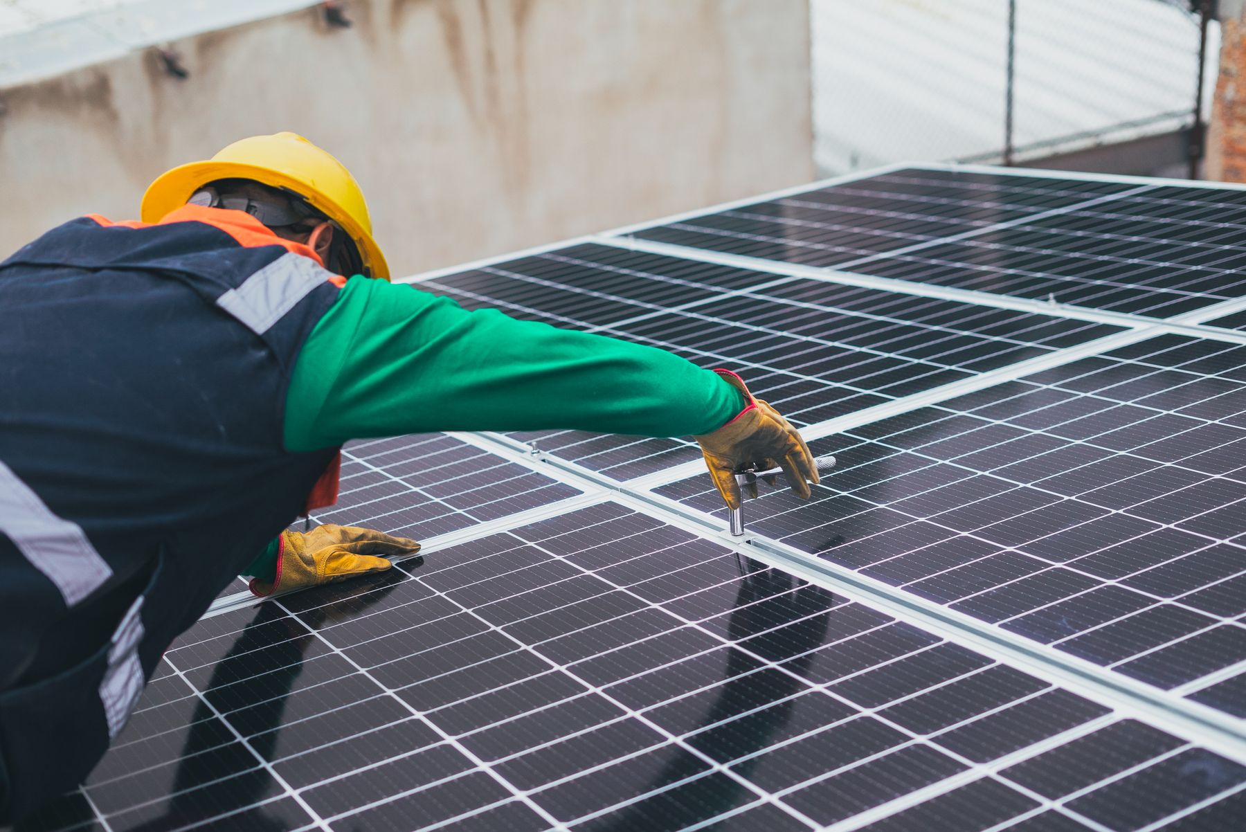 Technicien équipé installant des panneaux photovoltaïques sur une toiture